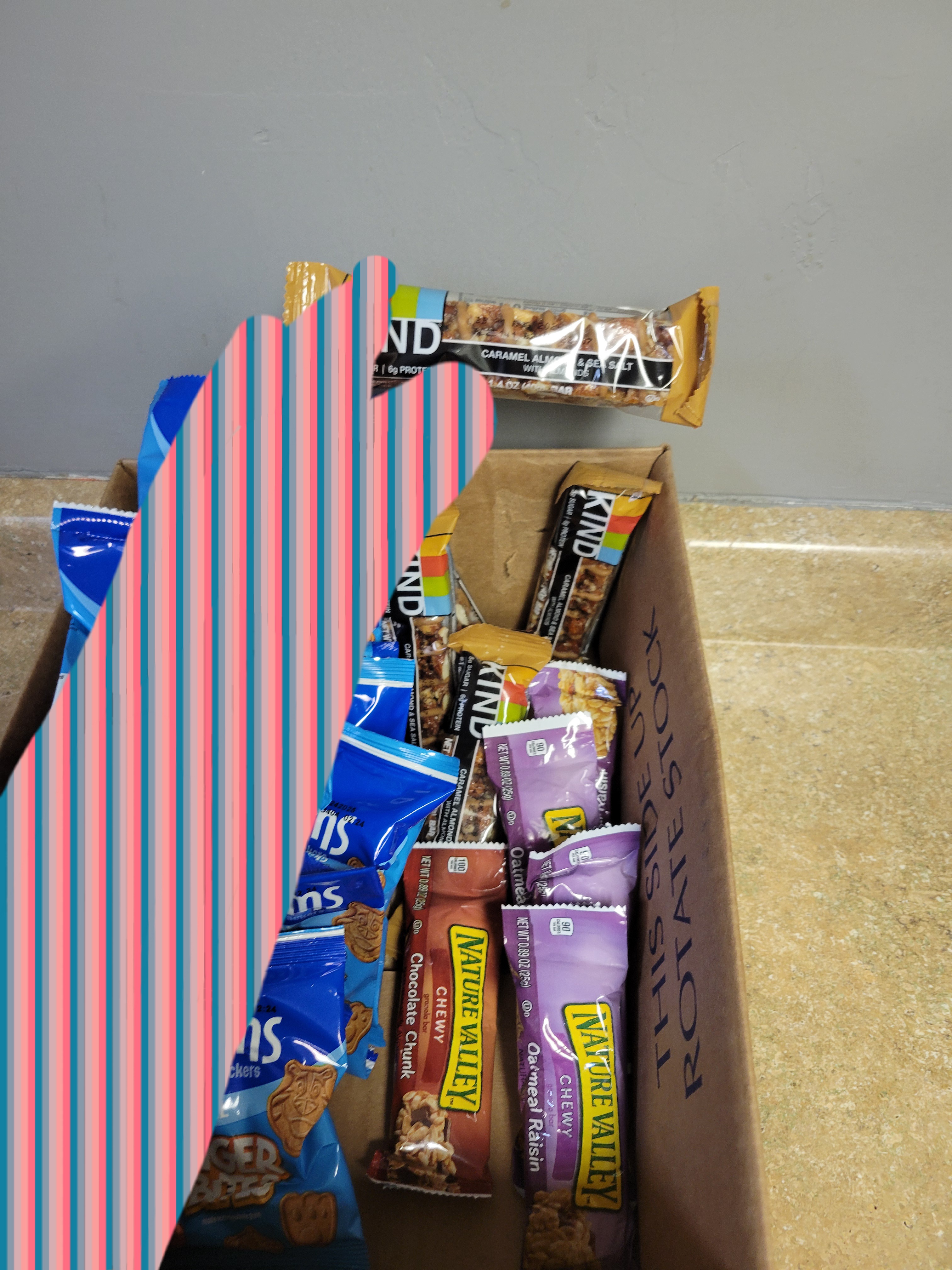 Hand holds granola bar on top of box of different granola bars.